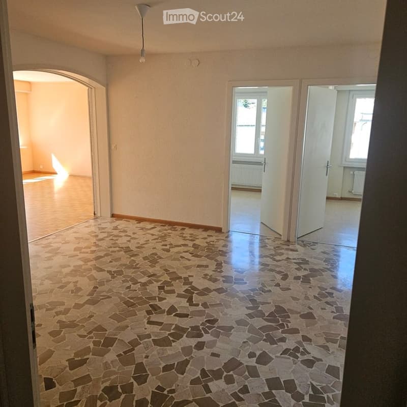 Empty room with beige walls, polished wooden floor, and a patterned tile entryway. No furniture or equipment visible.
