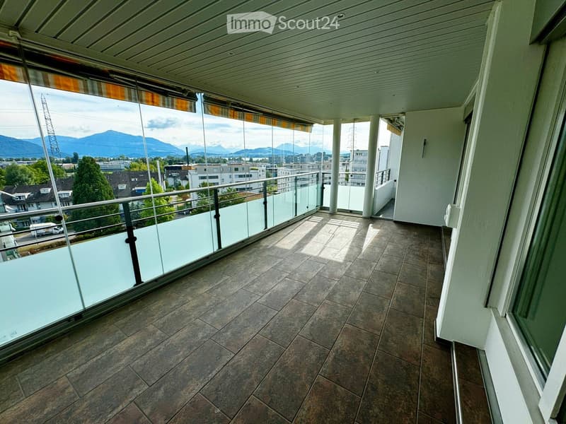 Spacious balcony with tiled flooring, glass railings, and scenic mountain views.
