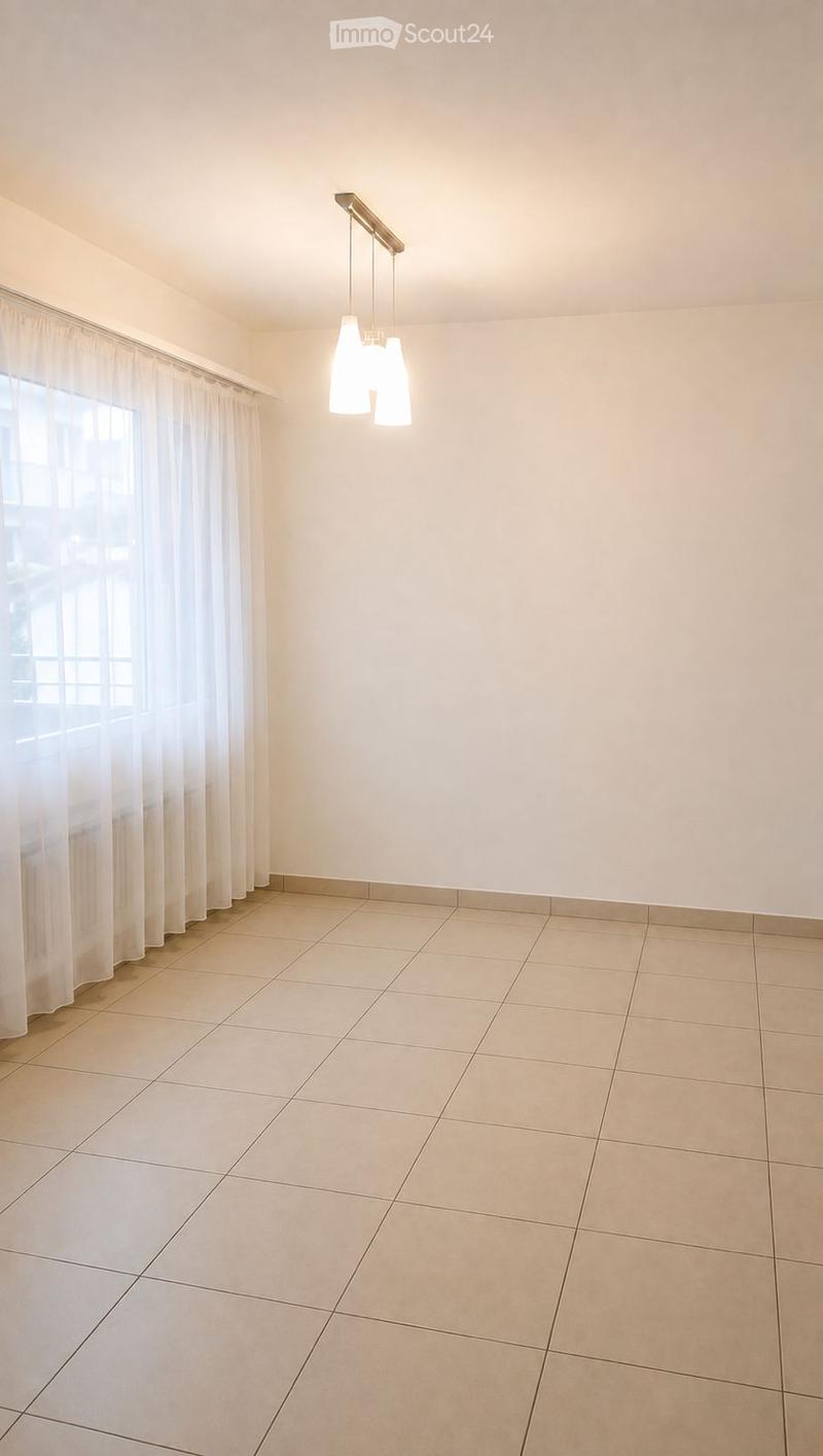 Empty room with tiled floor, white walls, large window with curtains, and a hanging light fixture.