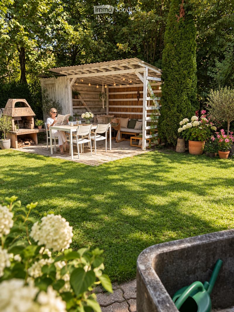 A well-maintained garden with a wooden pergola, outdoor seating area, dining table, chairs, and a brick pizza oven. The space is surrounded by lush greenery and potted plants.