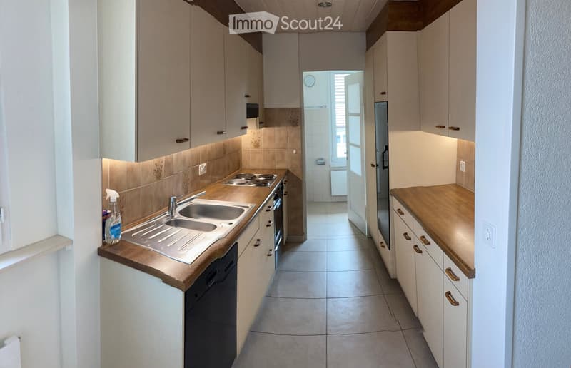 Modern kitchen with light-colored cabinets, wooden countertops, stainless steel sink, and built-in appliances including an oven and dishwasher.