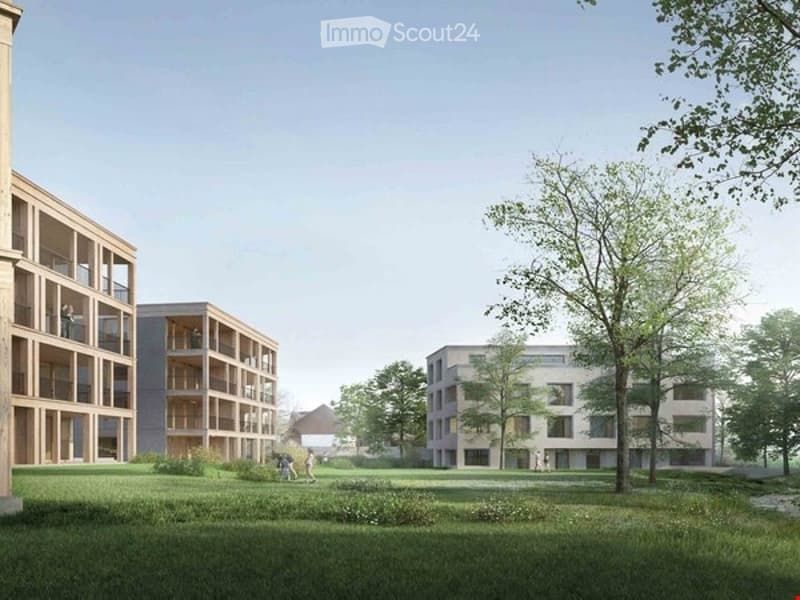 A modern residential complex with multiple apartment buildings, balconies, and a spacious green lawn area.