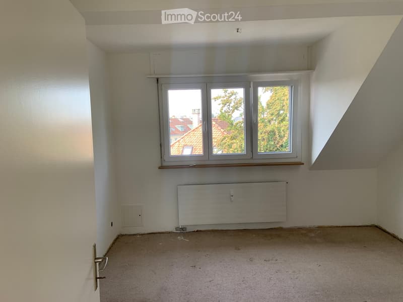 Empty room with white walls, a window, a radiator, and a door.