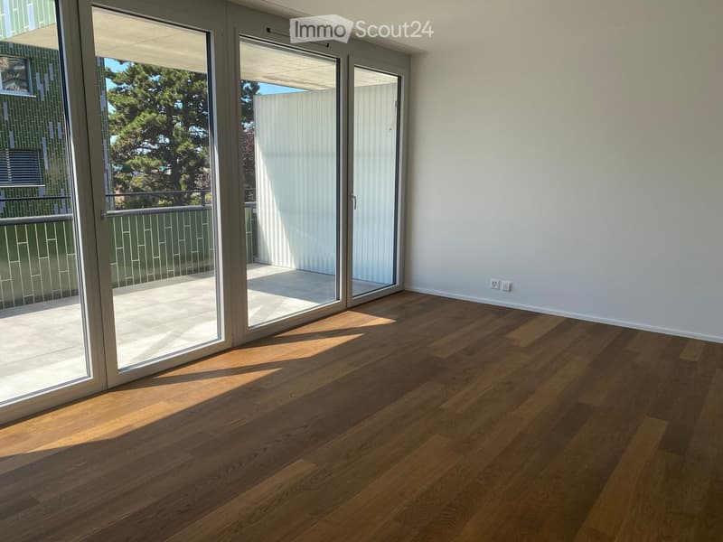 Empty room with wooden flooring and large sliding glass doors leading to a balcony.