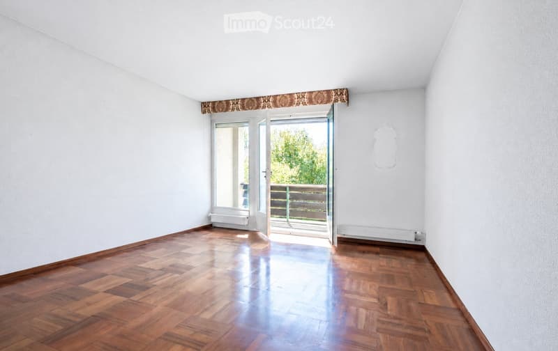 Empty room with wooden flooring, white walls, and a large open doorway leading to a balcony or terrace.
