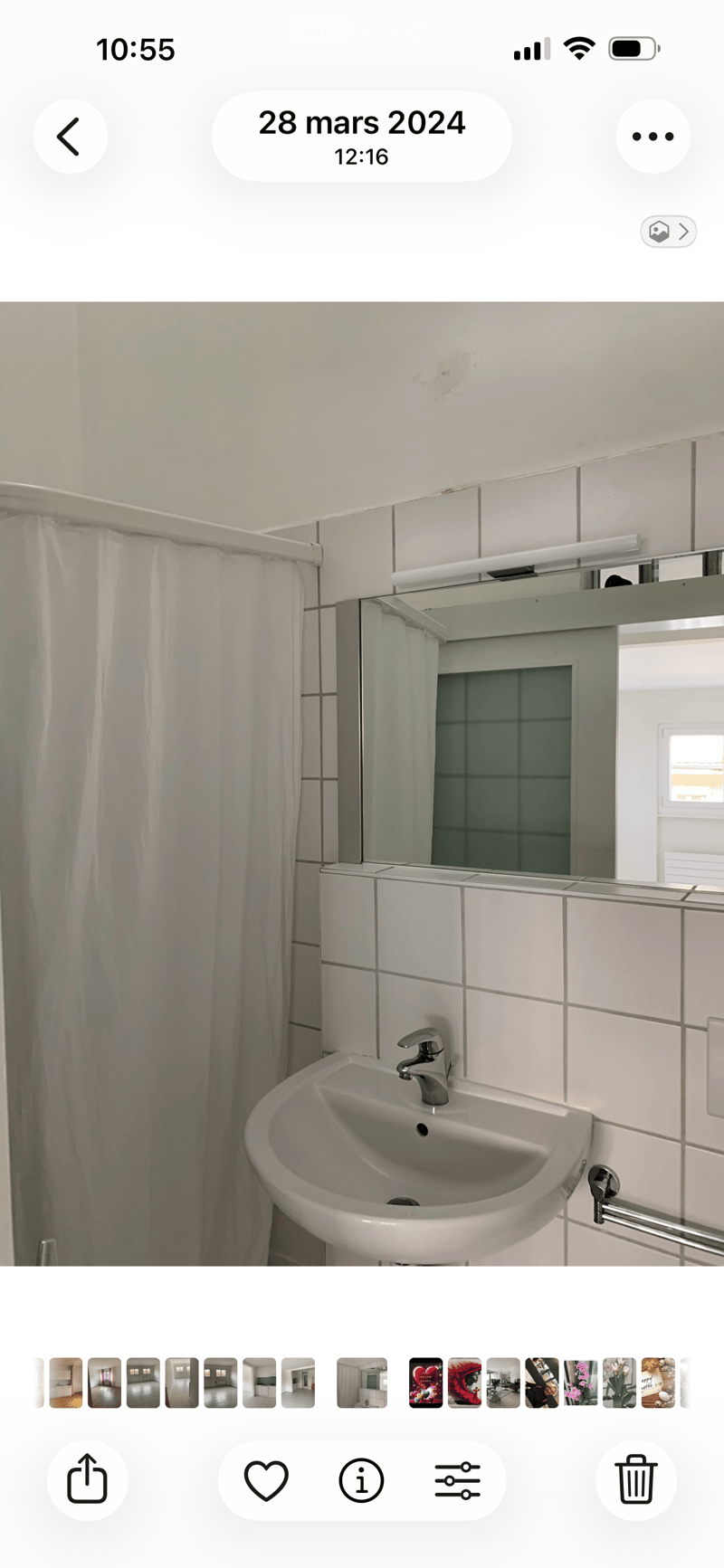 Bathroom with a white sink, silver faucet, large mirror, and a white shower curtain.