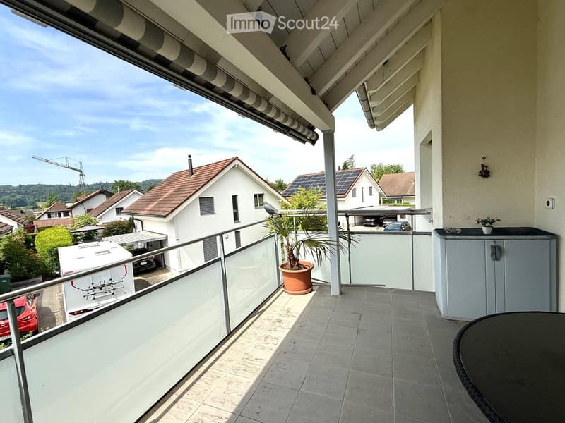Balcony with tiled floor, metal railing, small table, potted plant, and cabinet.