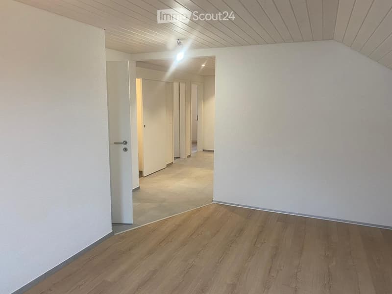 Empty hallway with wooden flooring and white walls, featuring a glass door leading to another room.