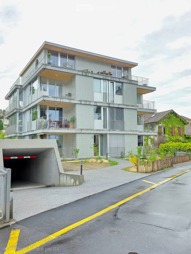 Modern multi-story building with balconies, large windows, and a covered garage entrance.
