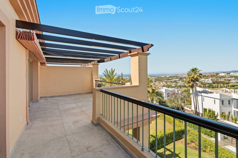 Balcony with wooden pergola, metal railing, and scenic view of the sea and surrounding area.