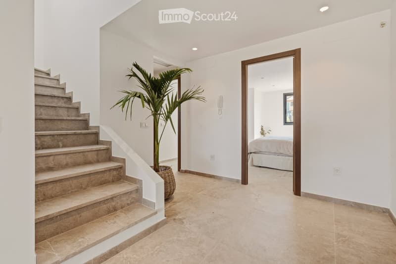 Modern hallway with a stone staircase, potted plant, and an open doorway leading to a bedroom.