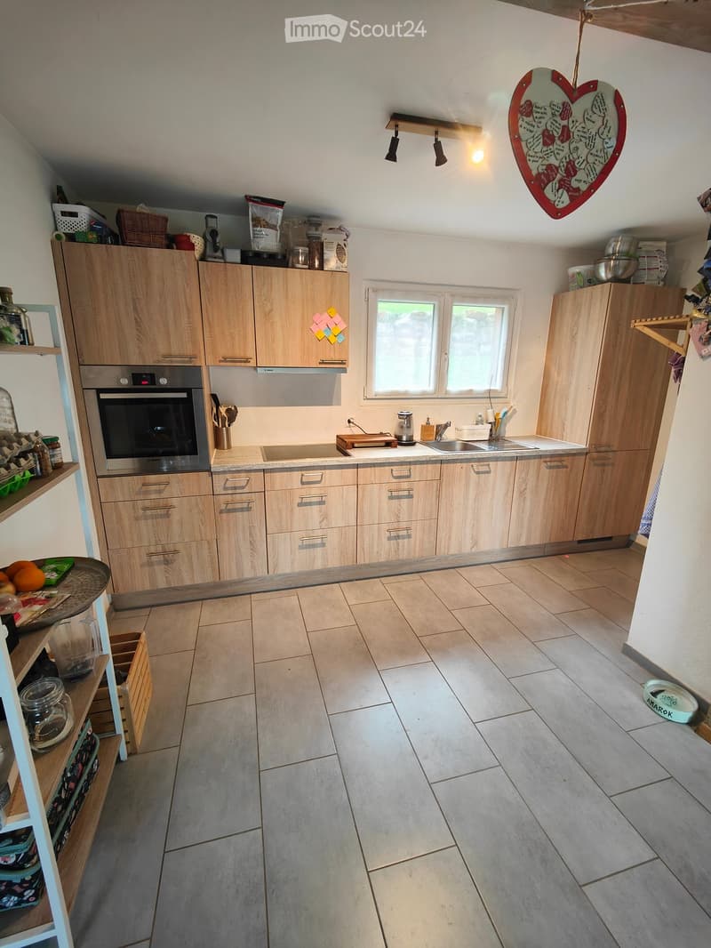 Modern kitchen with light wooden cabinets, stainless steel oven, sink, and countertop. Includes various kitchen items and appliances.