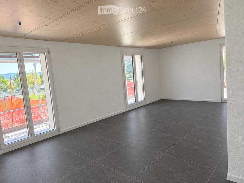 Empty room with grey tiled floor, white walls, and large sliding glass doors leading to an outdoor area.