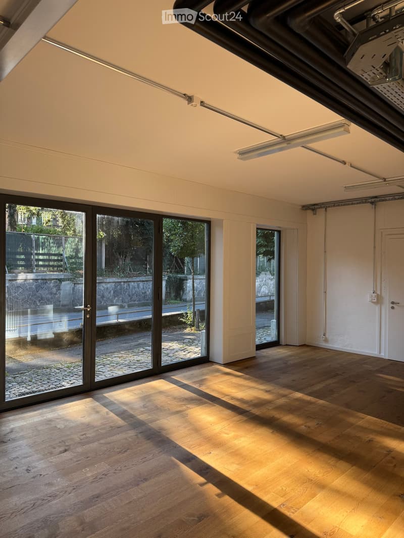 Empty room with wooden flooring, large glass sliding doors, and exposed ceiling beams.
