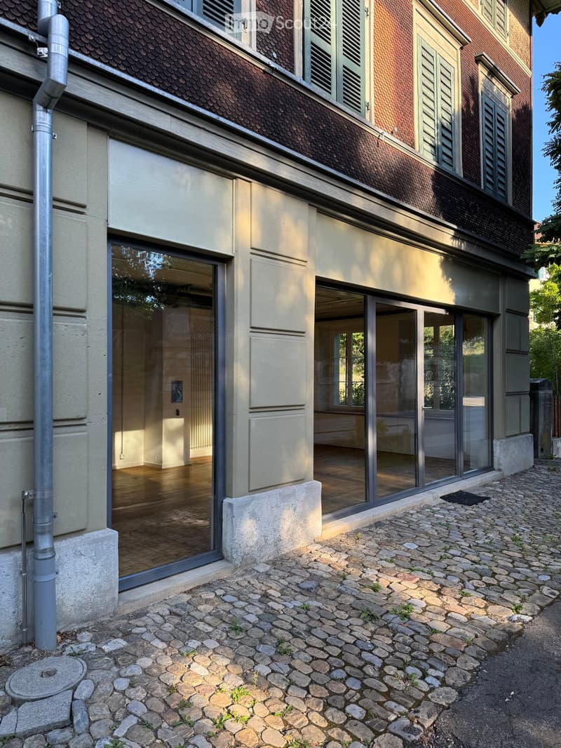 Modern building with large glass windows and a cobblestone pathway leading to the entrance.