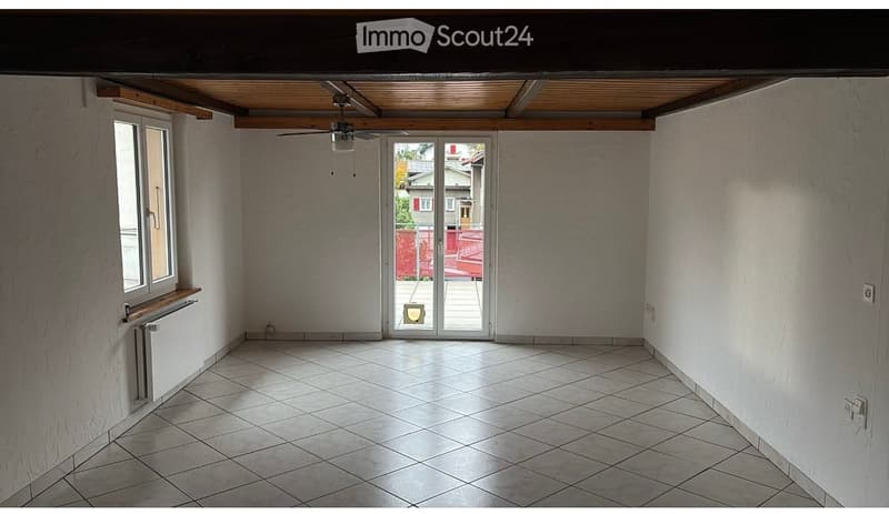 Empty room with tiled floor, white walls, large sliding glass doors leading to a patio, and a ceiling fan.