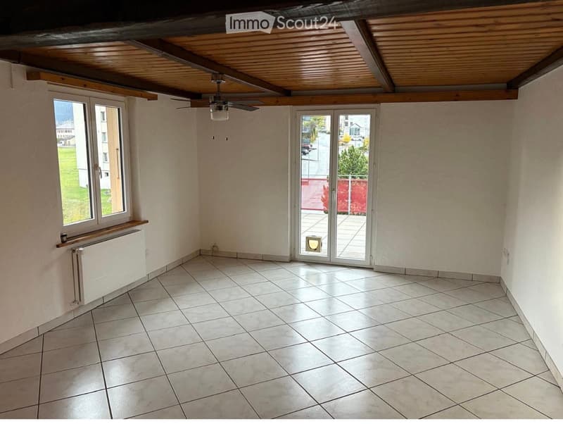 Empty room with tiled floor, white walls, large window, sliding glass door leading to a balcony, and a ceiling fan.