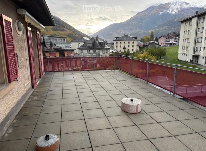 Balcony with tiled floor, metal railing, and scenic mountain view in the background.