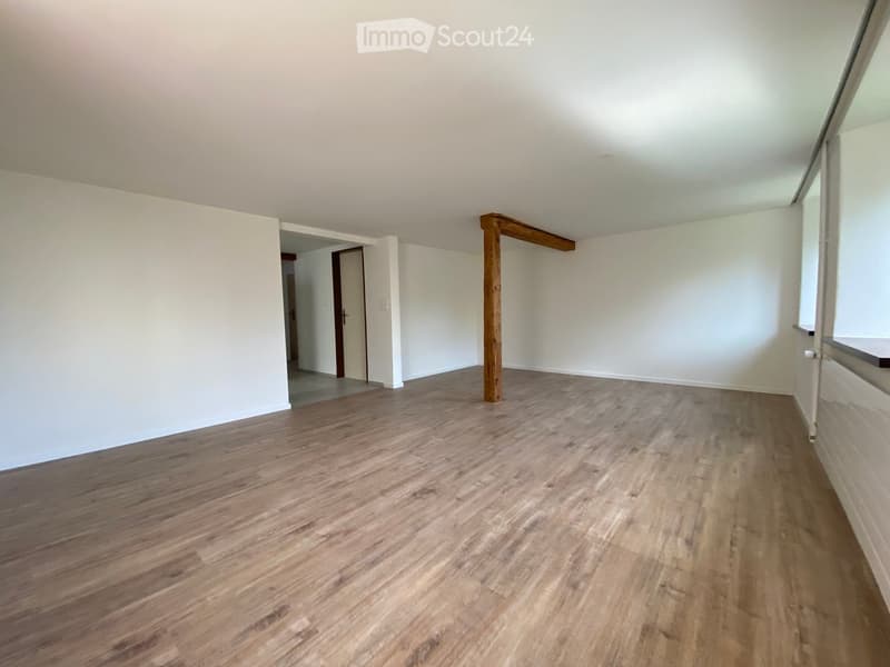 Empty room with wooden flooring, white walls, and a wooden beam in the center. No furniture or equipment is present.