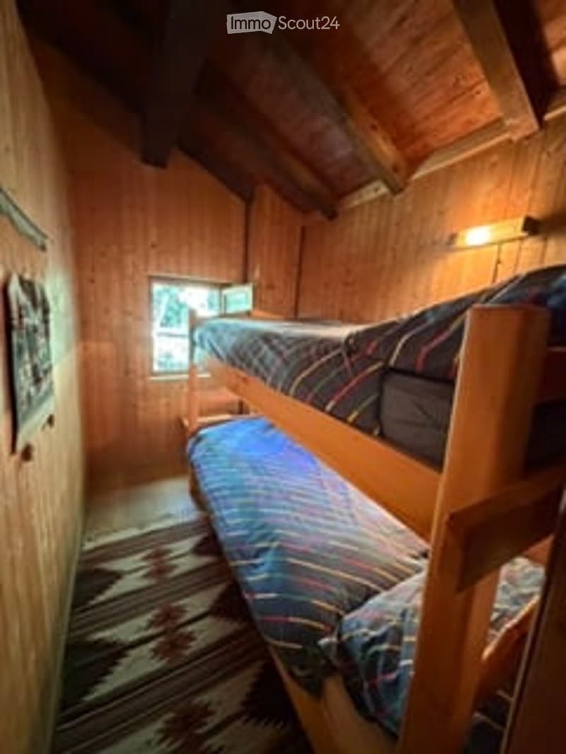 Cozy wooden bedroom with bunk beds, a window, and a wall-mounted light fixture.