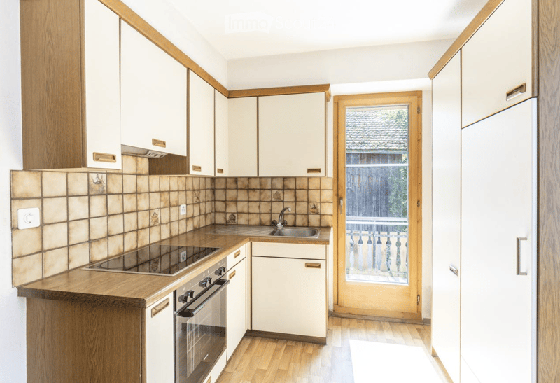 Modern kitchen with wooden cabinets, tiled backsplash, and stainless steel appliances including an oven and sink.