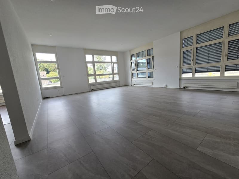 Empty room with large windows, tiled floor, and white walls. No furniture or equipment present.
