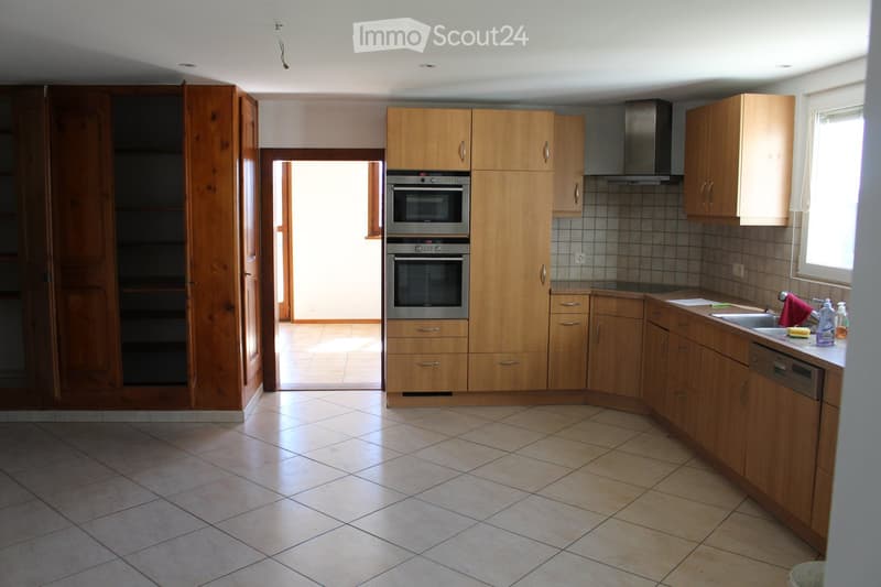 Modern kitchen with wooden cabinets, stainless steel appliances, tiled floor, and a window providing natural light.