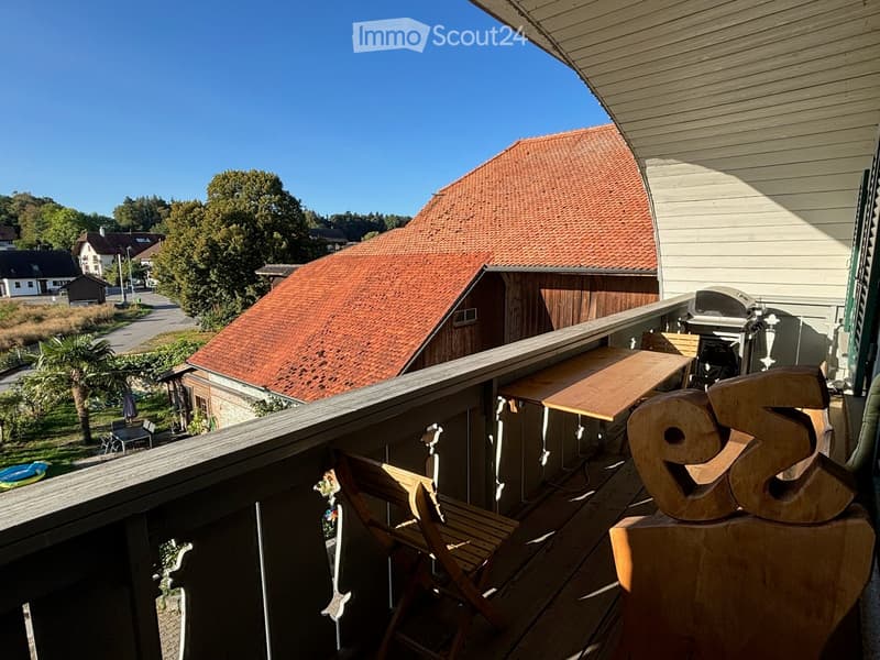 Balcony with wooden decking, outdoor furniture including a table and chairs, and a large decorative wooden sign with the number "95".