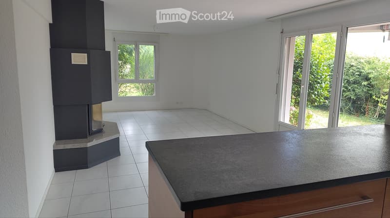 Empty room with white walls, tiled floor, fireplace, large window, and sliding glass door leading to outdoor area.