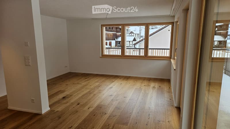Empty room with wooden flooring, large windows, and neutral-colored walls. No furniture or equipment present.