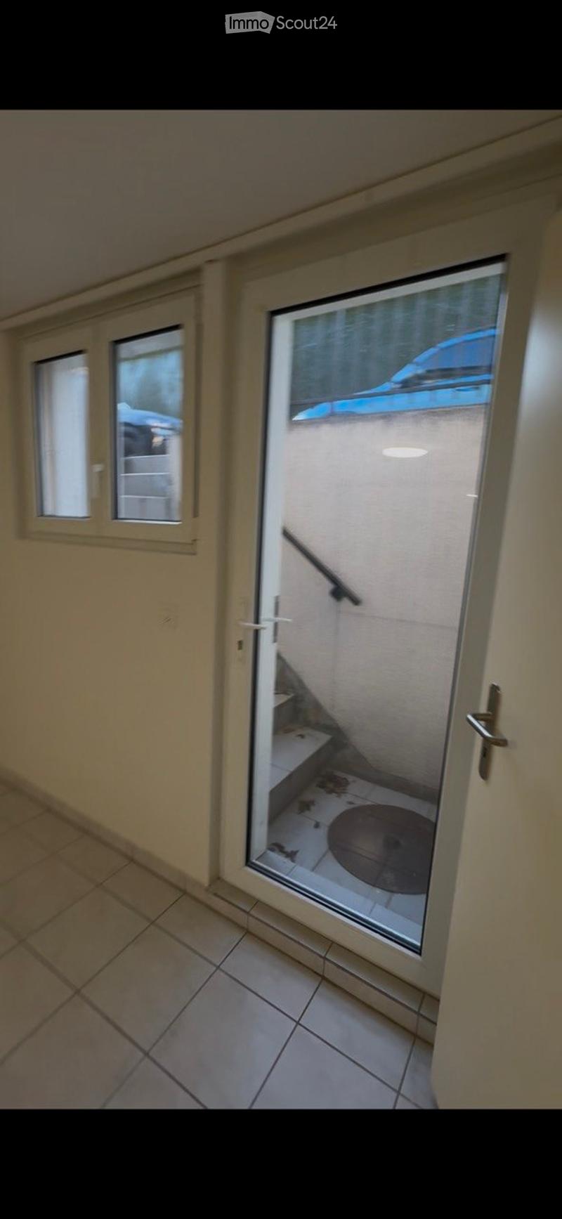 Balcony with tiled floor, glass door leading to a small outdoor area with a staircase and a circular platform.