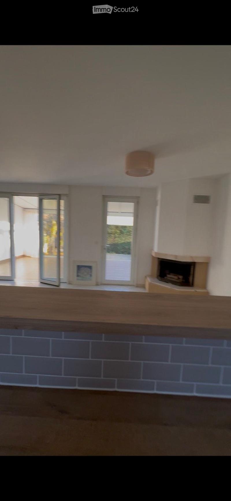 Empty room with a fireplace, large windows, and a wooden floor. No furniture or equipment is present.