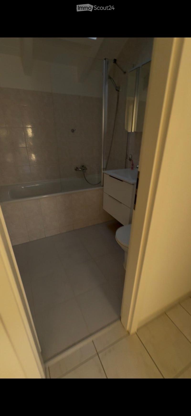 Modern bathroom with a bathtub, toilet, sink, and a glass-enclosed shower area. The space features tiled walls and floor, and a mirror above the sink.