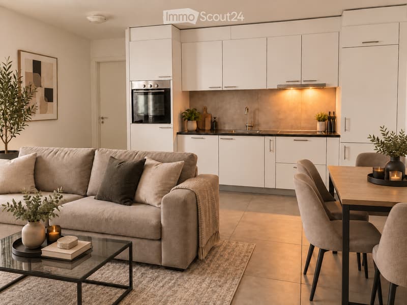 Modern open-plan living and dining area with a grey sofa, coffee table, dining table with chairs, integrated kitchen featuring white cabinets, an oven, and a sink. Decorative elements include potted plants, candles, and a framed picture on the wall.