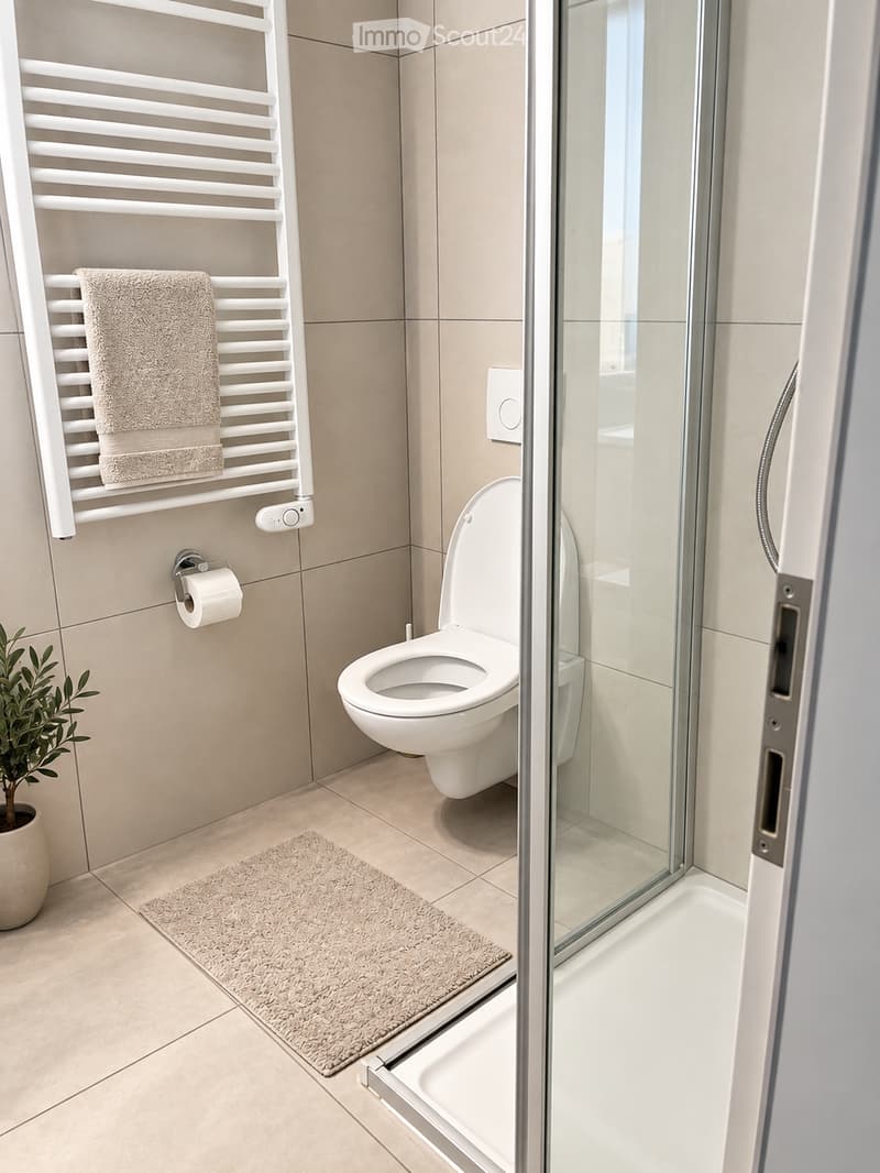 Modern bathroom with a toilet, towel rack, towel, toilet paper holder, glass-enclosed shower, bath mat, and a small plant in a pot.