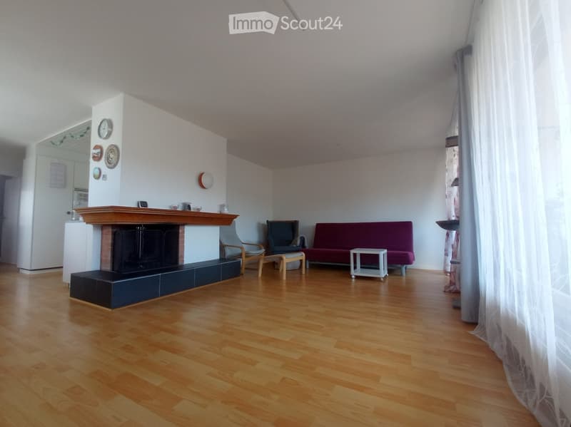 Living room with wooden flooring, fireplace, sofa, chairs, and a small table.