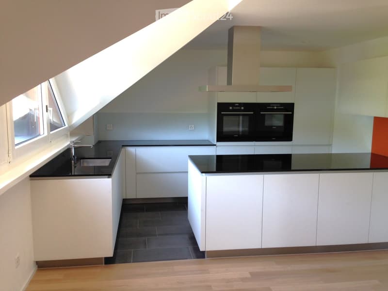 Modern kitchen with white cabinets, black countertops, and stainless steel sink and faucet. Features built-in ovens and ample storage space.