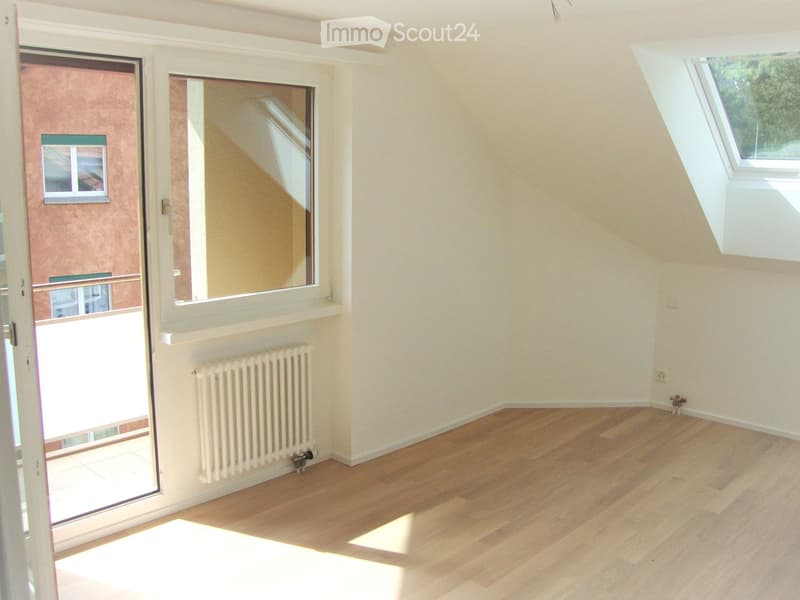 Empty room with wooden flooring, white walls, radiator, large window, and sliding door leading to a balcony.