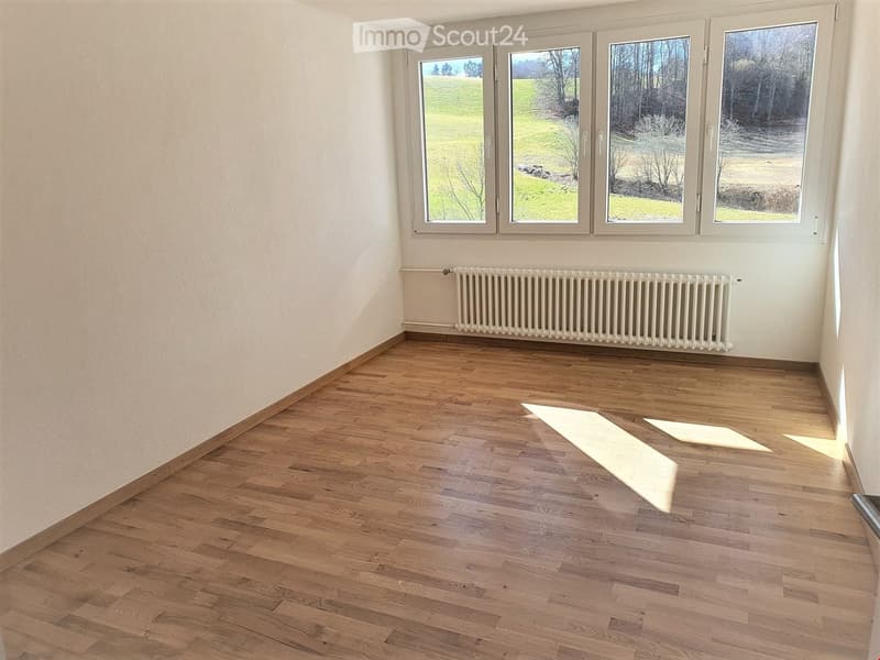 room with hardwood floor, three windows, white radiator