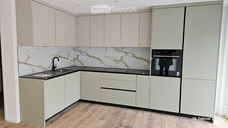 White marble countertop, stainless steel sink, faucet, oven and refrigerator in the corner, white cabinets, wooden floor