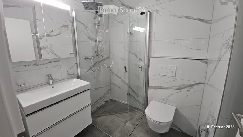 white walls and floor tiles, large mirror, sink, shower area, toilet