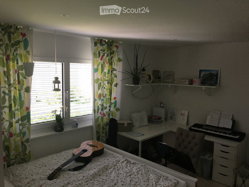 Cozy bedroom with a bed, guitar, desk, chair, keyboard, shelves, and decorative items.