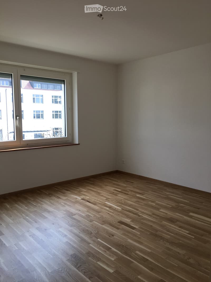 Empty room with wooden flooring and large window, no furniture or equipment.