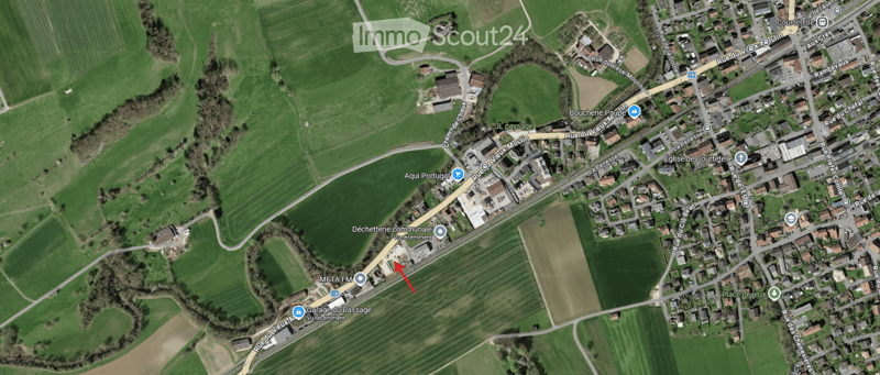 Aerial view of a rural area with a parking lot, buildings, and surrounding fields.