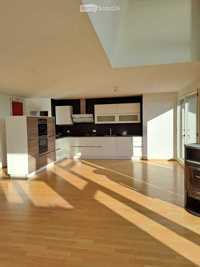 An open kitchen with modern wooden floors, black and white countertops, and built-in appliances.