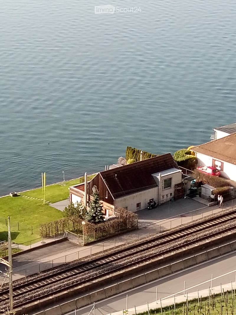 aerial view of a water body with a house, garden and parking place