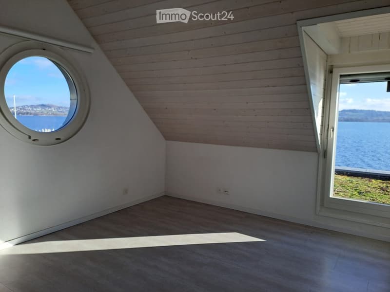 Empty room, wooden ceiling, large circular window, lake view
