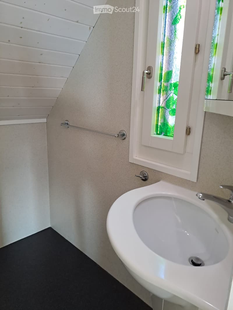 Corner bathroom with a sink, window, and towel rack.