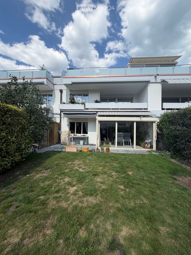 Modern two-story house with large windows, balconies, and a well-maintained lawn in the front yard.