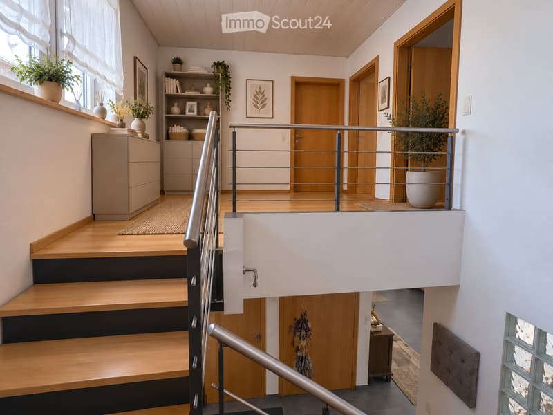 Modern hallway with wooden flooring, staircase with metal railing, built-in cabinetry, and decorative plants on shelves and windowsills.